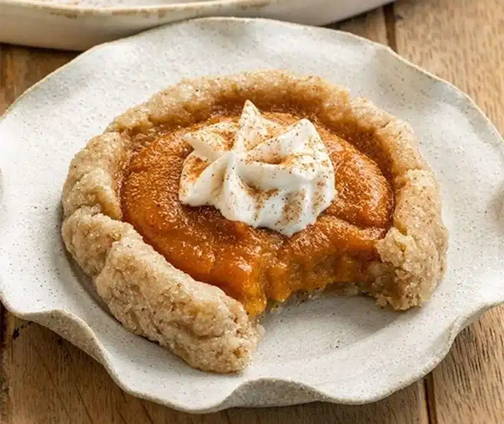 Vegan pumpkin pie cookies on a rustic wooden table with autumn leaves